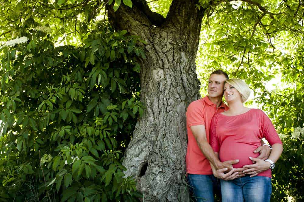A couple leans on a Walnut Tree.