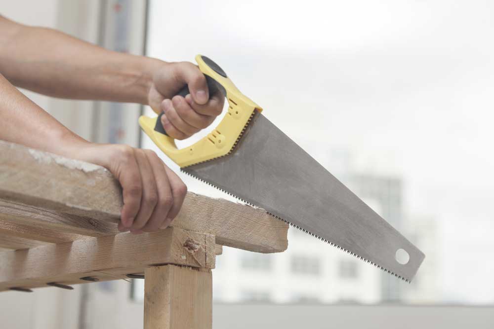 A Man cutting wood with a saw
