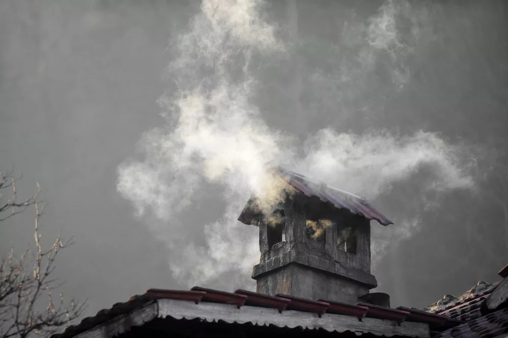 House with a smoking chimney on a cold winter day. 