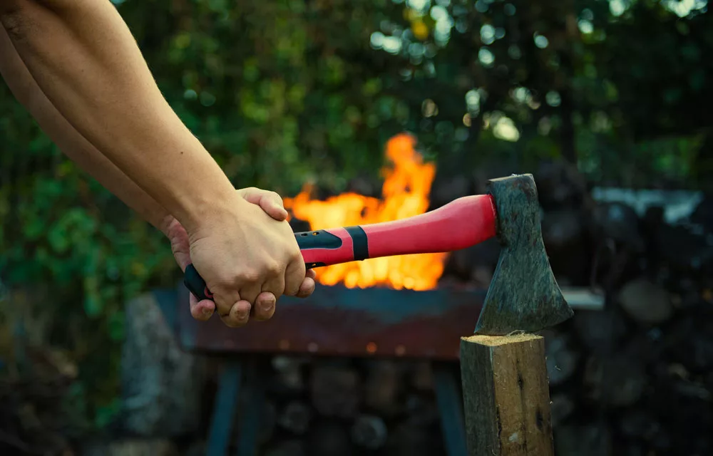 A Man uses a Hatchet with two hands.