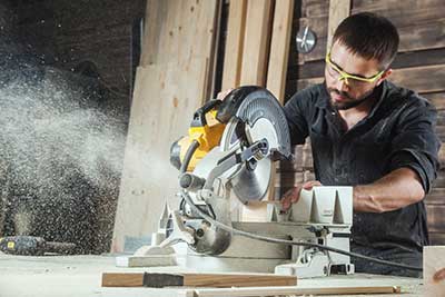 A carpenter using a miter saw