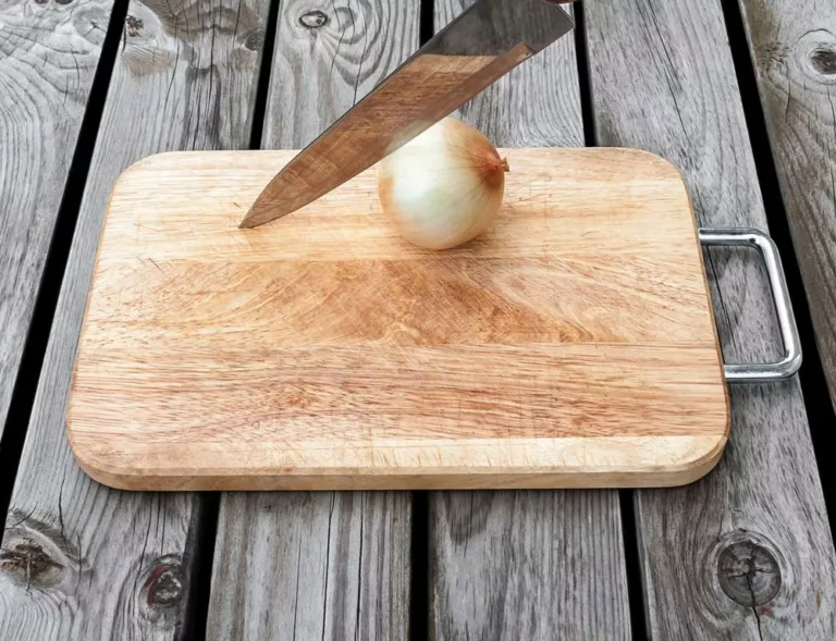A knife and onion on a cutting board