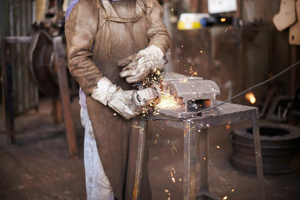 A man grinding metal in a workshop 