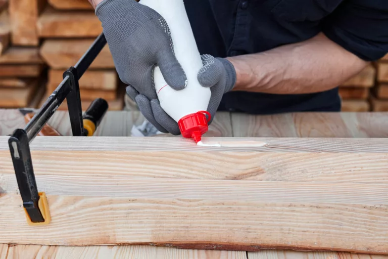 A male carpenter using glue on wood